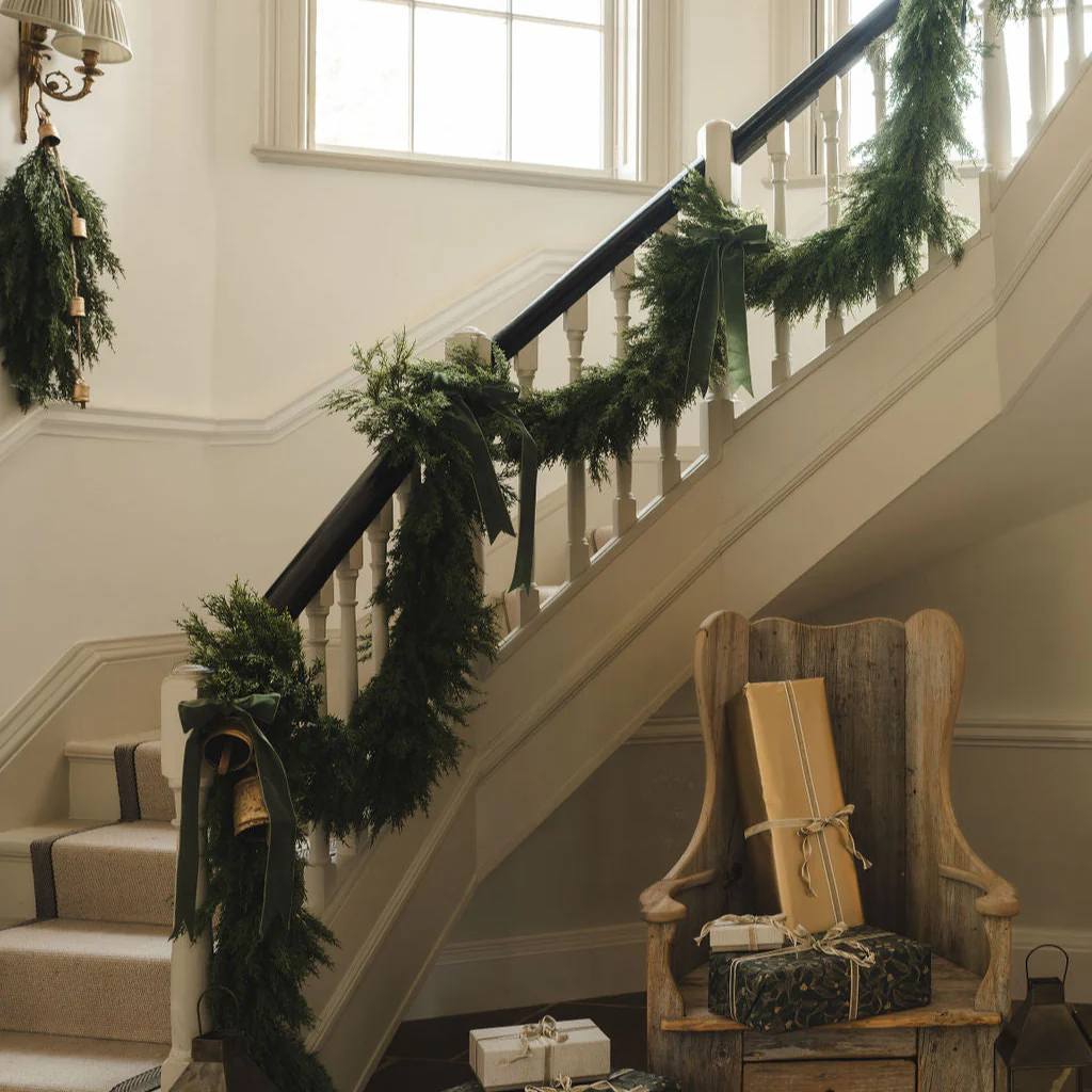 Decorative staircase with greenery and wrapped gifts in a home setting