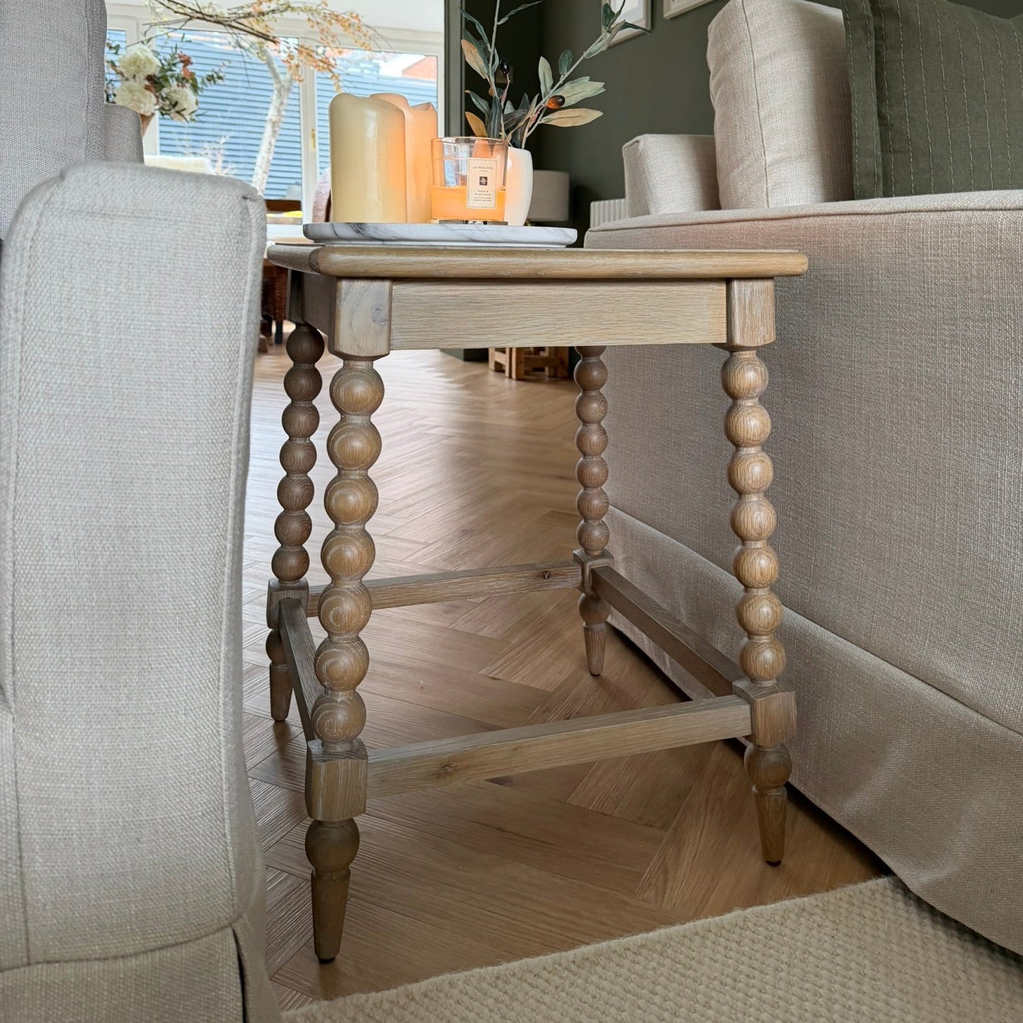 Living room with a wooden side table, gray sofa, and decorative items.