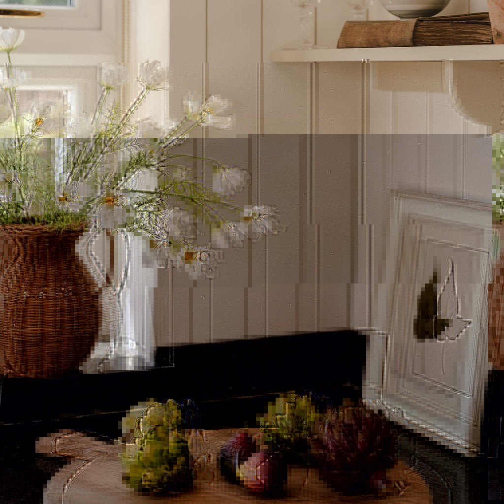 Wooden cutting board with fruits and a vase of flowers on a kitchen counter.