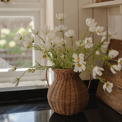 Wicker vase with white flowers on a windowsill in a home setting