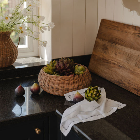 Kitchen counter with a basket of fruit, pears, and a cutting board.