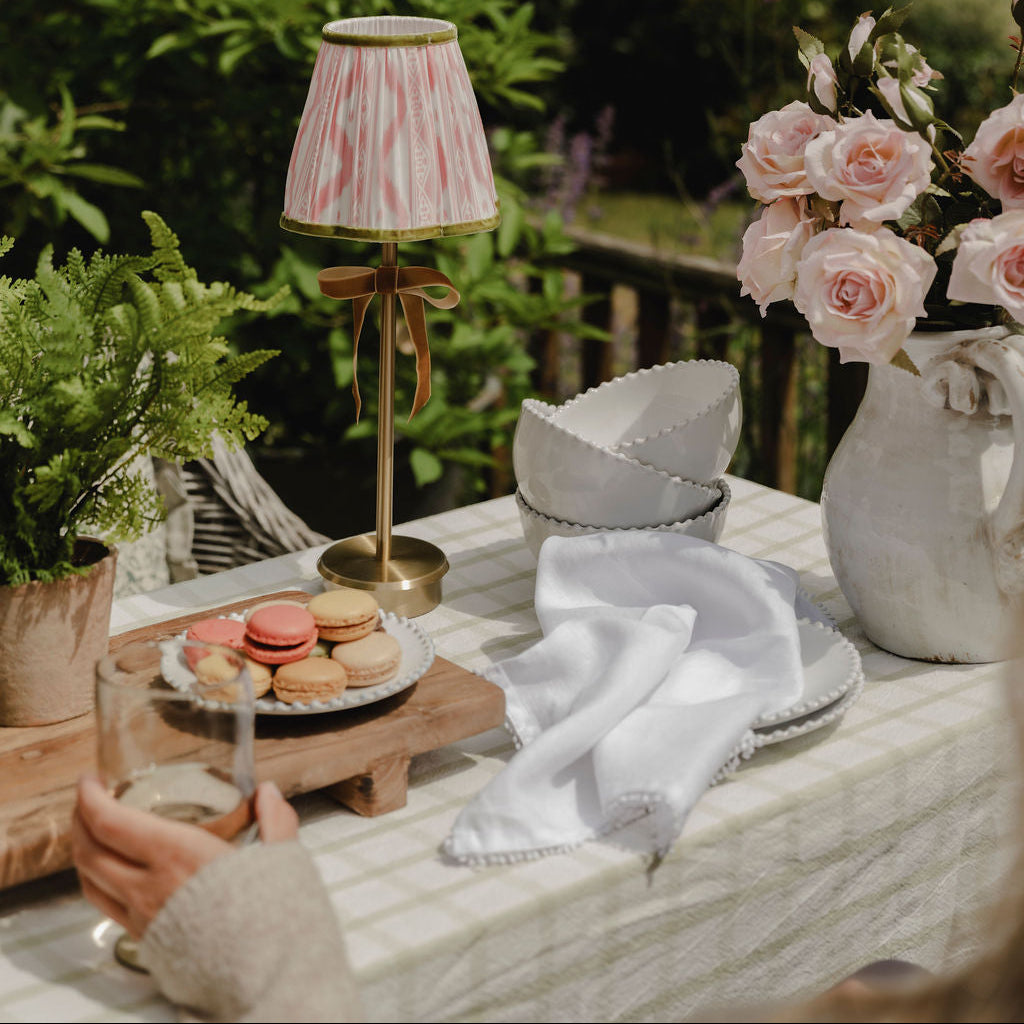 Outdoor setting with a table featuring a lamp, macarons, and flowers.